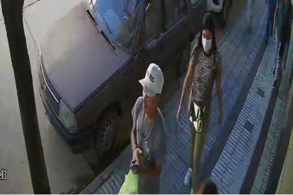 La ladrona escapando a pie, con barbijo, cartera brillosa y pantal&oacute;n verde.