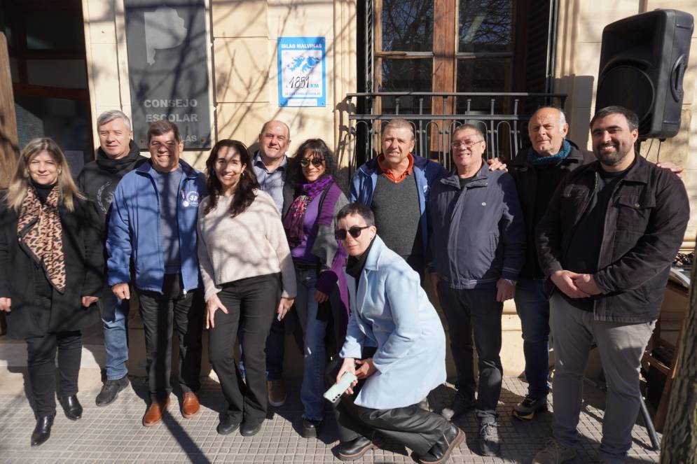 Consejeros y combatientes. De fondo, la placa en el frente del organismo.